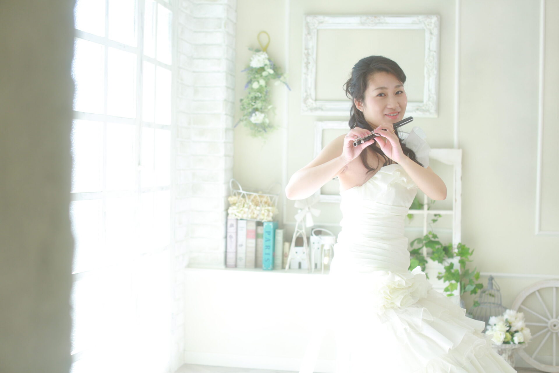 柔らかな日差しを受ける室内でピッコロを吹く由佳先生